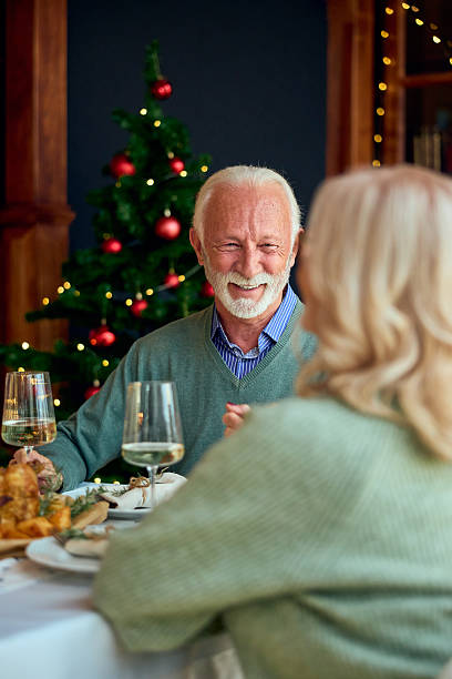 istock Happy Elder Gentleman At Christmas Dinner With Partner, Festive Table, And Christmas Tree 2242748932