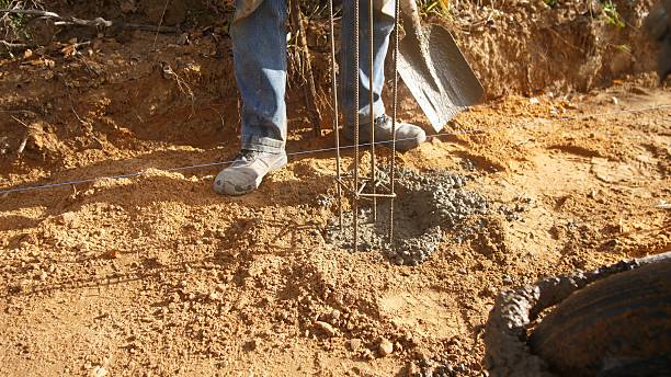 istock concrete work scene, worker guides concrete mix into prepared hole with rebar reinforcement in rural construction site 2242750539