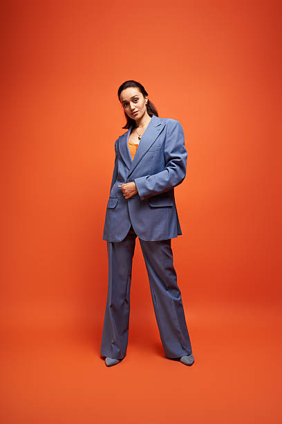 istock Brunette model showcases trendy blue suit against vibrant orange backdrop 2242750712