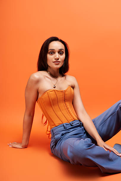 istock Stunning brunette models blue pants and orange corset in vibrant studio setting 2242750933