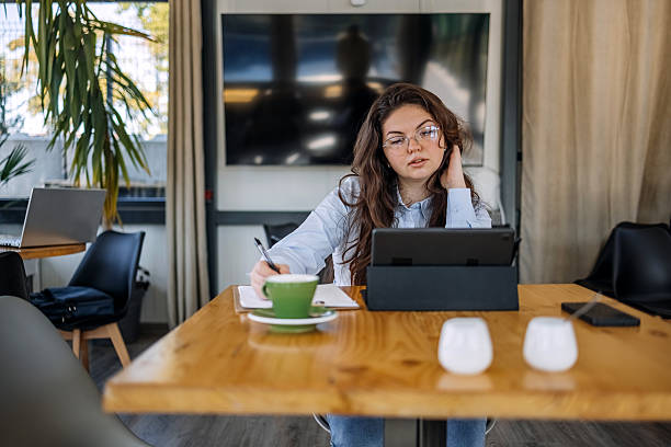 istock Young businesswoman working using wireless technology while sitting at cafe taking a coffee break 2242754073