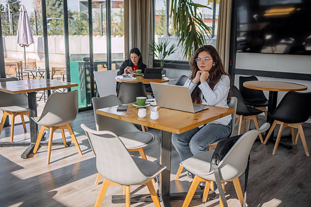 istock Young businesswoman working using wireless technology while sitting at cafe taking a coffee break 2242754100