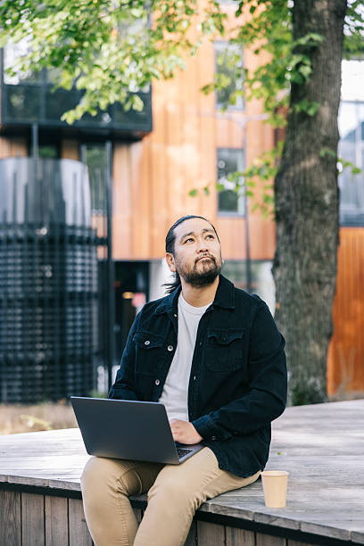 istock Thoughtful man with laptop outdoors on a wooden deck, enjoying work in an urban park setting 2242758038