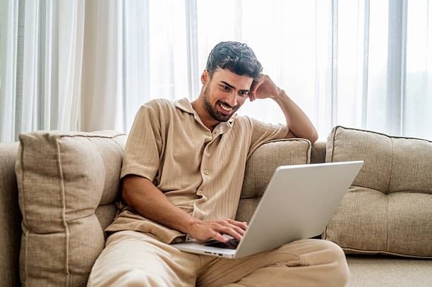 istock Relaxed Man On Sofa Using Laptop At Home, Casual Beige Outfit, Cozy Tech Moment 2242760198