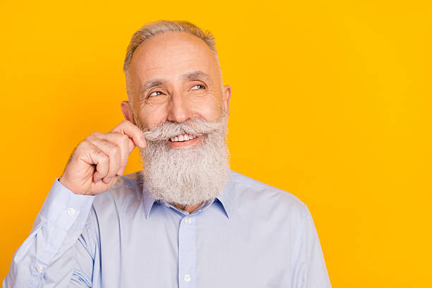 istock Close-up portrait of attractive cheerful middle-aged man touching beard thinking copy space isolated over gray pastel color background 2242762610
