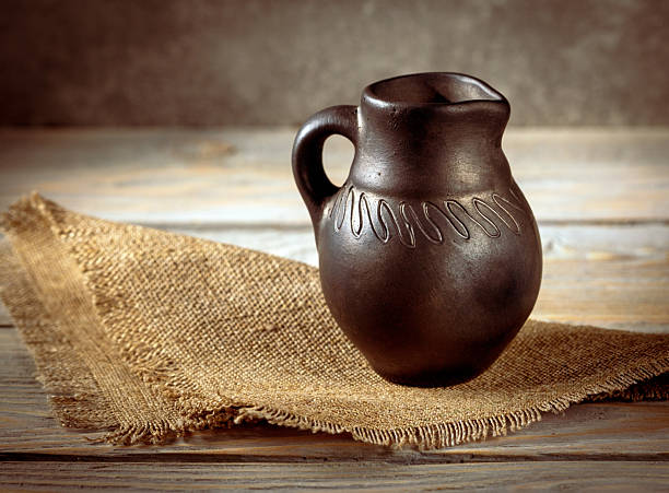 This close-up photography captures the beautiful details of a vintage pitcher alongside a rustic burlap napkin, perfect for showcasing classic home decor and dining aesthetics.