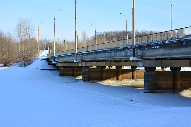 Concrete Bridge Spanning a Snow-Covered River on a Clear Winter Day