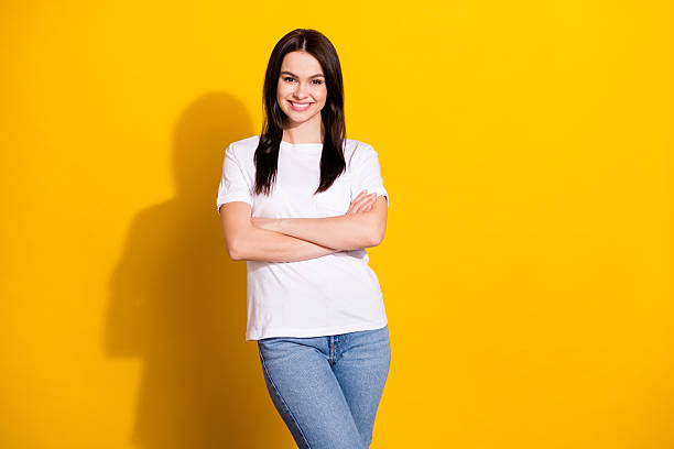 istock Photo of charming pretty young lady dressed white t-shirt smiling hands folded empty space isolated yellow color background 2242766708