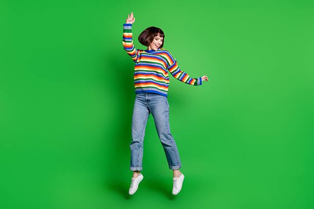istock Full length photo shiny adorable young lady dressed colorful pullover jumping high smiling isolated green color background 2242768164