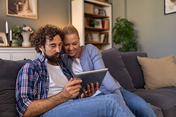 istock A couple having time to themselves, watching their memories on the digital tablet while sitting on the sofa in the living room. 2242769287