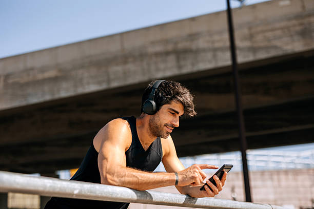 istock Handsome athlete using smartphone and headphones outdoors 2242773133