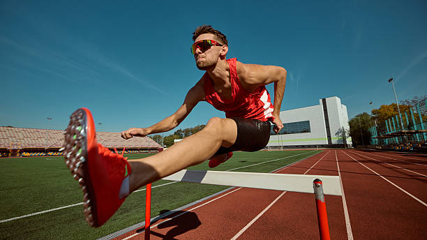 istock Focused athlete jumping hurdle on track during athletic competition 2242774012