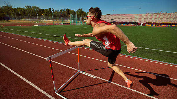 istock Hurdler in red outfit leaping over barrier on track with determination 2242774018