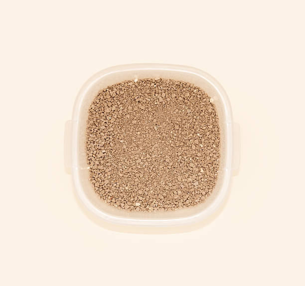 istock Brown cat litter granules in a transparent container against a soft pastel background that highlights their texture and color, perfectly suited to the concept of pet care 2242774232