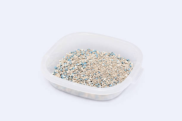 istock Transparent container holds textured granules of cat litter with blue flecks highlight the natural absorbent materials on a white background, suitable for pet care. 2242774248