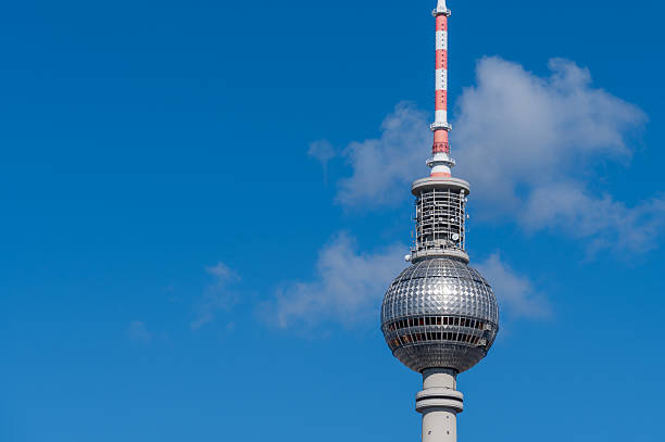 The iconic Berlin Television Tower stands tall in a clear blue sky, surrounded by modern buildings. A captivating urban scene depicting architectural brilliance and a clean, serene atmosphere.