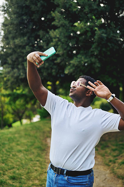 istock Young man taking selfie and posing with smartphone outdoors 2242776006