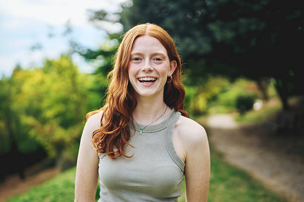 istock Smiling young woman standing outdoors in park on sunny day 2242776019