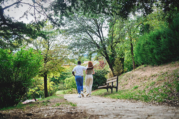 istock Couple walking together in green park on sunny day 2242776038