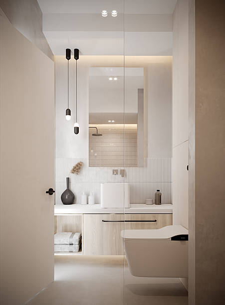 istock Modern minimalist bathroom interior with warm neutral tones and soft ambient lighting. Elegant white sanitary fixtures, textured wall tiles, light wood cabinetry, and subtle LED accents create a clean and sophisticated atmosphere. 2242776640