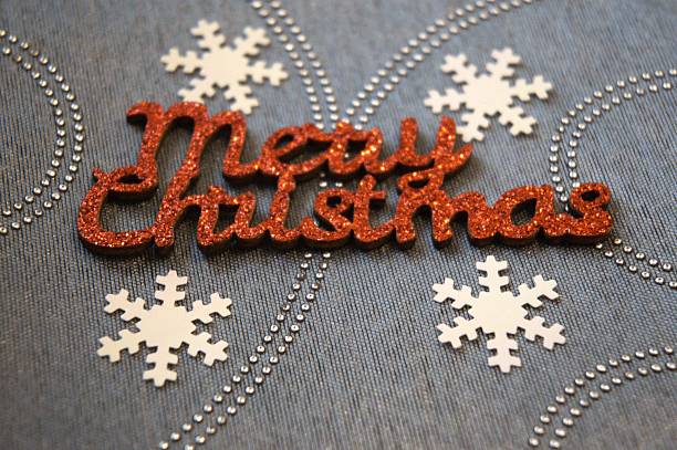 istock Shiny red Merry Christmas text surrounded by snowflake patterns on gray textured fabric, Copy Space 2242777811