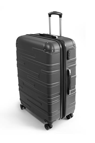 Modern black suitcase with retractable handle and four wheels photographed in studio against white background. Concept of travel, packing and vacation
