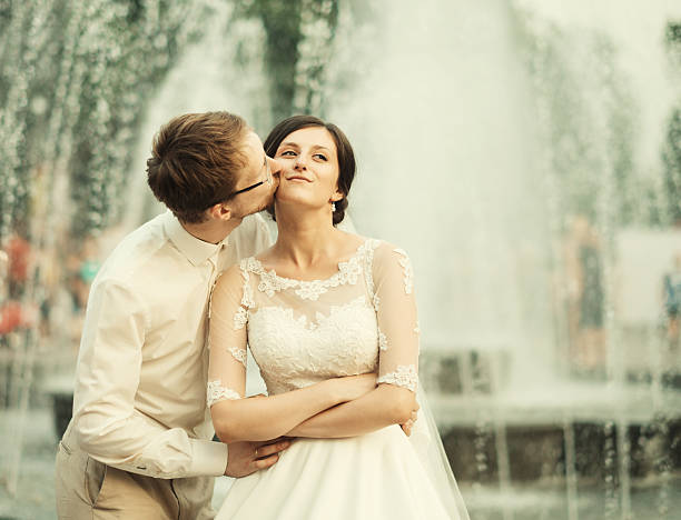 Bride with white wedding dress playing with the water of a fountain
