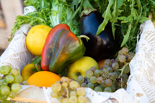 A beautifully arranged basket filled to the brim with various fresh fruits and vibrant vegetables, including sweet peppers and juicy grapes