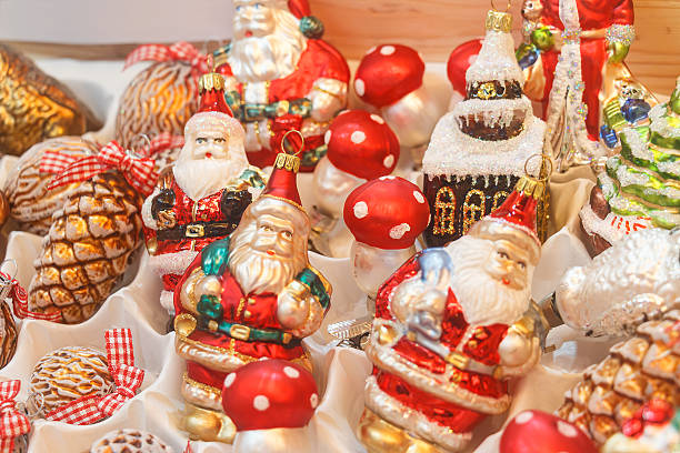 Beautiful Christmas tree balls made of glass in designs of Santa Clauses, Pine Cones, Fly Agaric Mushrooms, a Gingerbread House and a Christmas Tree, at a display of a booth at a Christmas market.