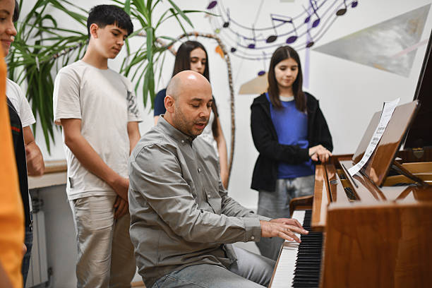 istock Group of Students Listening Closely as Professor is Explaining While Playing Piano 2242790663