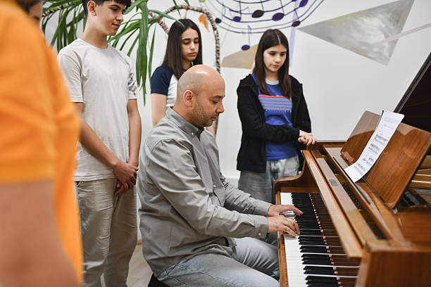 istock Group of Music Students Watching Professor Who’s Explaining at the Piano With Passion 2242790687