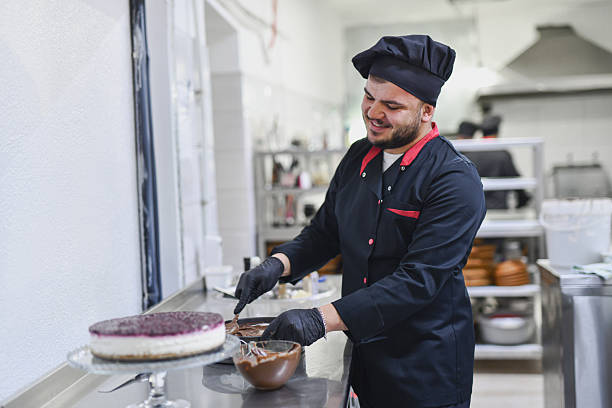 istock Chef In Black Uniform Decorating Chocolate Cake In Modern Kitchen Studio 2242792692