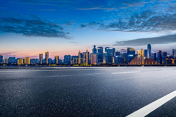 istock Empty asphalt highway leading towards the illuminated modern city financial district skyline at dusk in Hangzhou. 2242796098