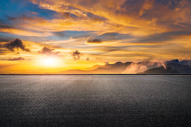 istock Empty asphalt ground with a dramatic mountain range landscape at spectacular golden sunset. 2242796266