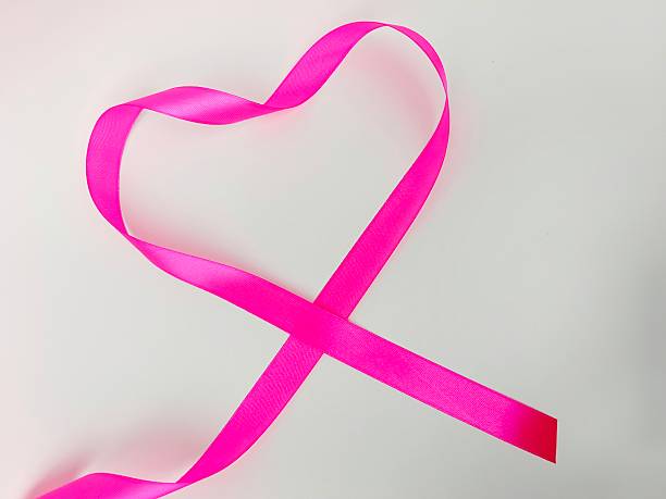 A vivid pink ribbon bends into a heart shape against a white background, creating a romantic, feminine mood. Ideal for Valentine, love, friendship and gift-giving themes in stock collections