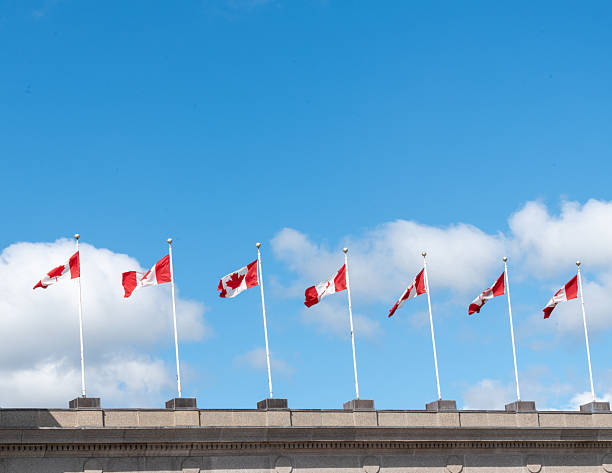 istock Canadian flags on a building with blue cloudy sky background 2242800581