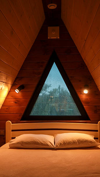 istock Cozy bedroom with a triangular window and wooden walls 2242807180