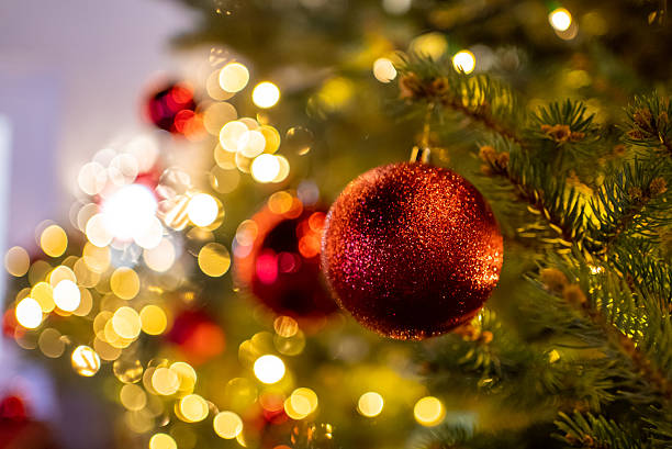 istock Red glitter christmas ornament hanging on tree with lights 2242809889