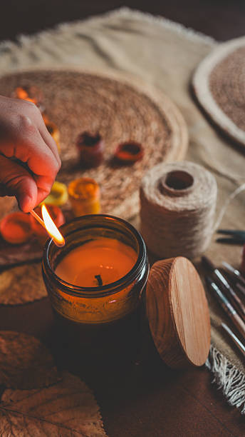istock Candle being lit with a match in a cozy, autumnal setting. 2242811831