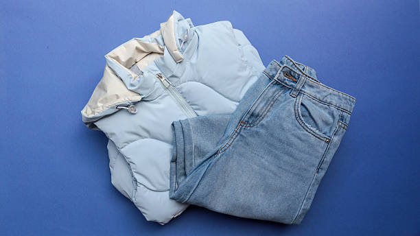 istock Stylish light blue puffer vest and jeans set on a vibrant blue background. 2242815286