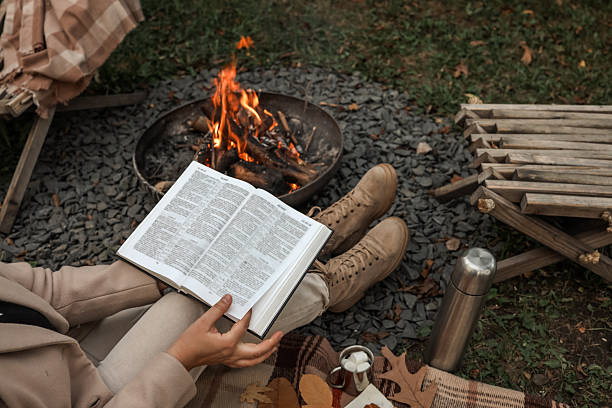 istock Reading by the campfire on a cozy autumn day with a warm drink and marshmallows. 2242815759