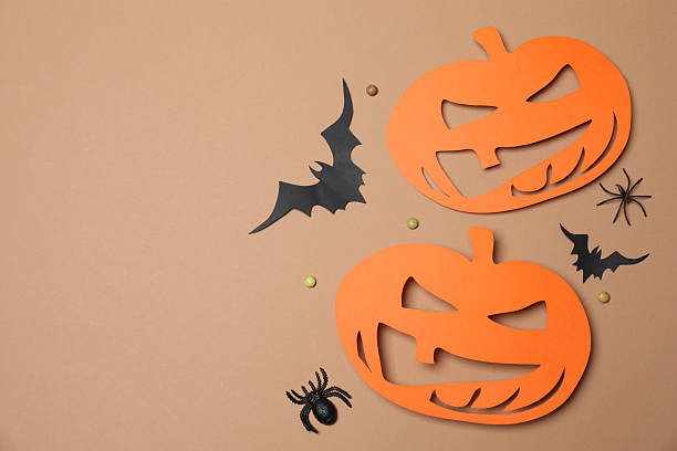 istock Elegant Halloween decor. Top view capturing thematic elements: small orange and golden pumpkins, insects, scary spiders, cobwebs, bats. Empty space for greetings or promotions. 2242819478