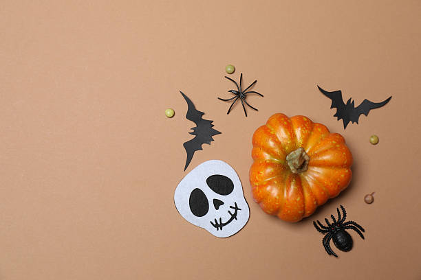 istock Elegant Halloween decor. Top view capturing thematic elements: small orange and golden pumpkins, insects, scary spiders, cobwebs, bats. Empty space for greetings or promotions. 2242819481