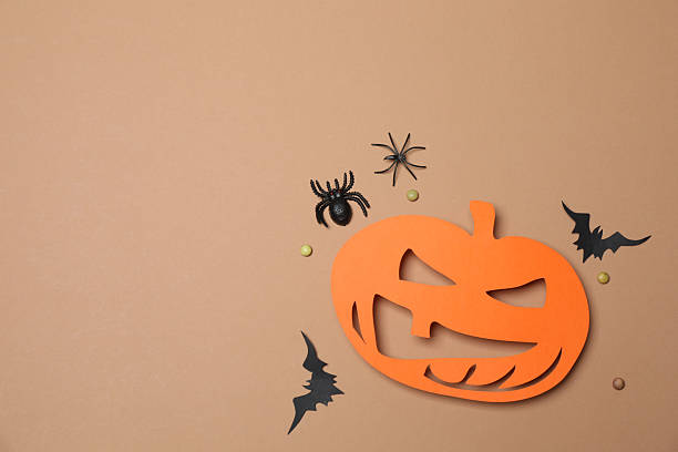 istock Elegant Halloween decor. Top view capturing thematic elements: small orange and golden pumpkins, insects, scary spiders, cobwebs, bats. Empty space for greetings or promotions. 2242819482