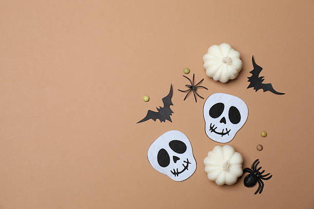 istock Elegant Halloween decor. Top view capturing thematic elements: small orange and golden pumpkins, insects, scary spiders, cobwebs, bats. Empty space for greetings or promotions. 2242819483