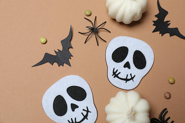 Elegant Halloween decor. Top view capturing thematic elements: small orange and golden pumpkins, insects, scary spiders, cobwebs, bats. Empty space for greetings or promotions.