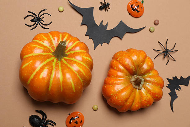 istock Elegant Halloween decor. Top view capturing thematic elements: small orange and golden pumpkins, insects, scary spiders, cobwebs, bats. Empty space for greetings or promotions. 2242819496