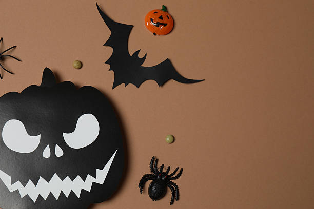 istock Elegant Halloween decor. Top view capturing thematic elements: small orange and golden pumpkins, insects, scary spiders, cobwebs, bats. Empty space for greetings or promotions. 2242819533