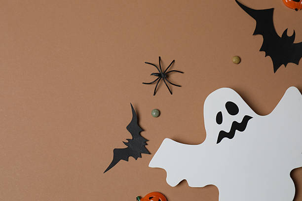 istock Elegant Halloween decor. Top view capturing thematic elements: small orange and golden pumpkins, insects, scary spiders, cobwebs, bats. Empty space for greetings or promotions. 2242819541