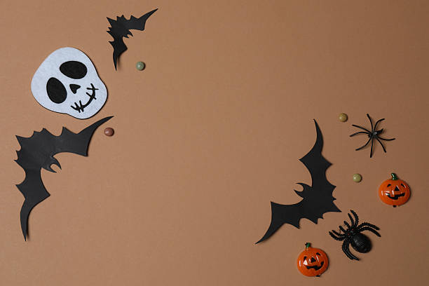 istock Elegant Halloween decor. Top view capturing thematic elements: small orange and golden pumpkins, insects, scary spiders, cobwebs, bats. Empty space for greetings or promotions. 2242819548